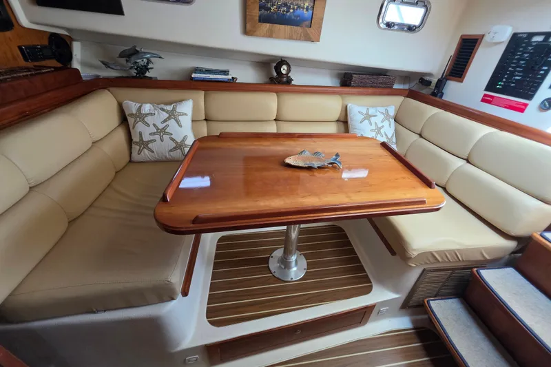 Interior of 2005 Mainship 34 Pilot Sedan Rum Runner II with cozy seating and wooden table.