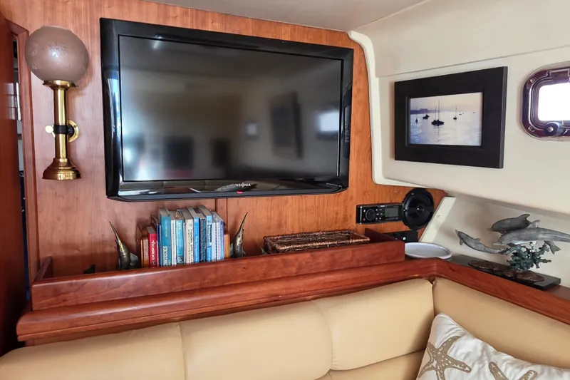Interior of 2005 Mainship 34 Pilot Sedan with TV, books, and nautical decor.