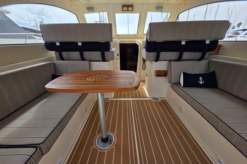 Interior of 2005 Mainship 34 Pilot Sedan Rum Runner II with striped seating and wooden table.