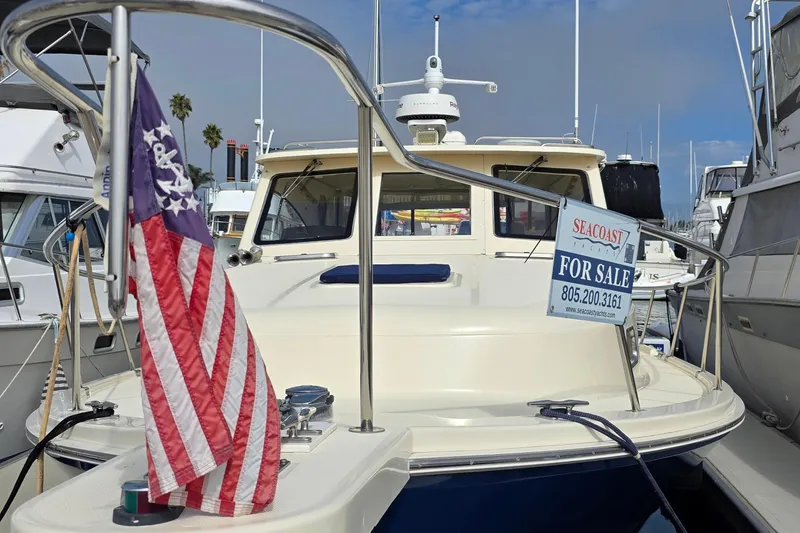 2005 Mainship 34 Pilot Sedan Rum Runner II for sale at marina, American flag displayed.