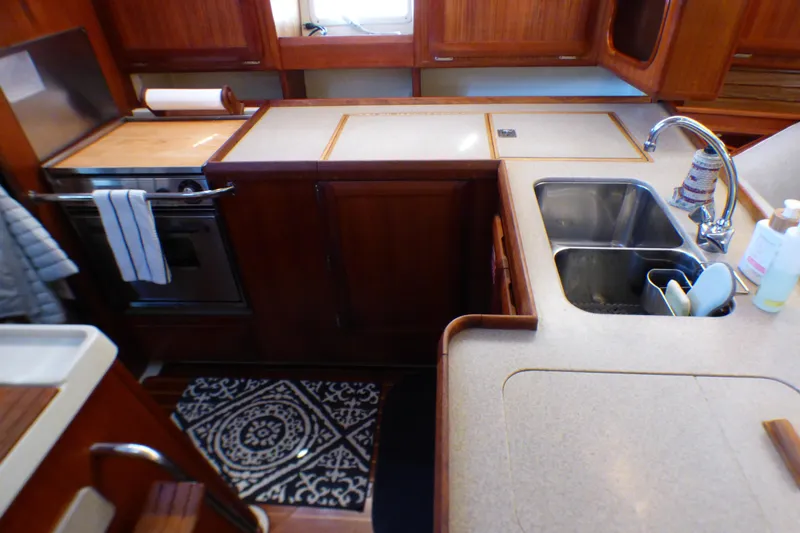 Interior of 1993 Hunter 40.5 yacht kitchen with sink, stove, and wooden cabinetry.