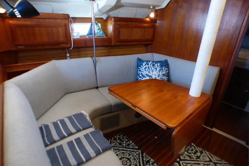 Cozy interior of 1993 Hunter 40.5 sailboat with wooden table and cushioned seating.