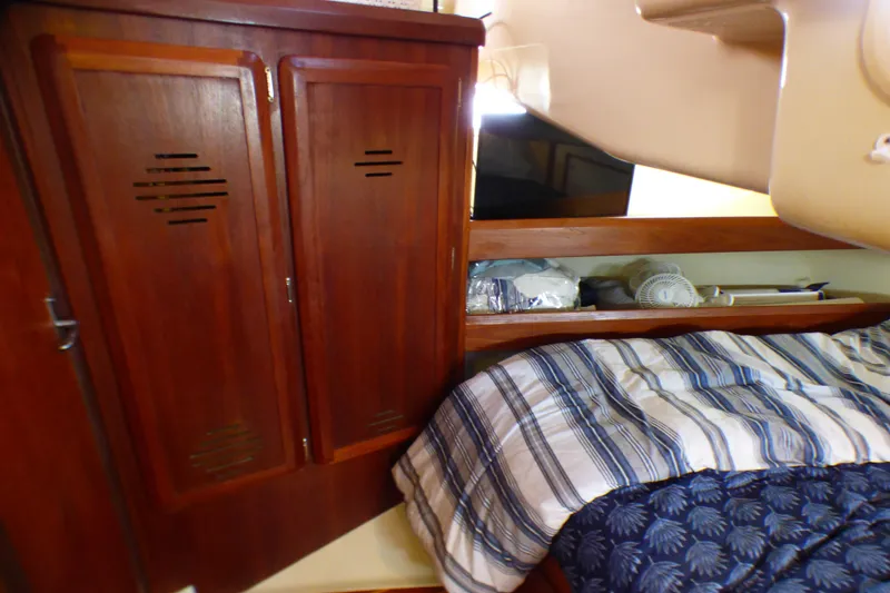 Cozy cabin interior of 1993 Hunter 40.5 sailboat with wooden cabinets and striped bedding.