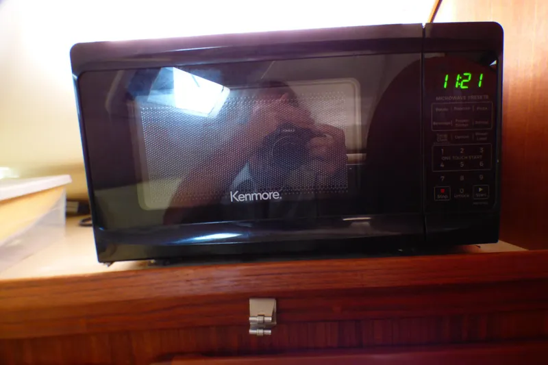 Kenmore microwave on wooden shelf, digital clock displaying 11:21, in a 1993 Hunter 40.5.