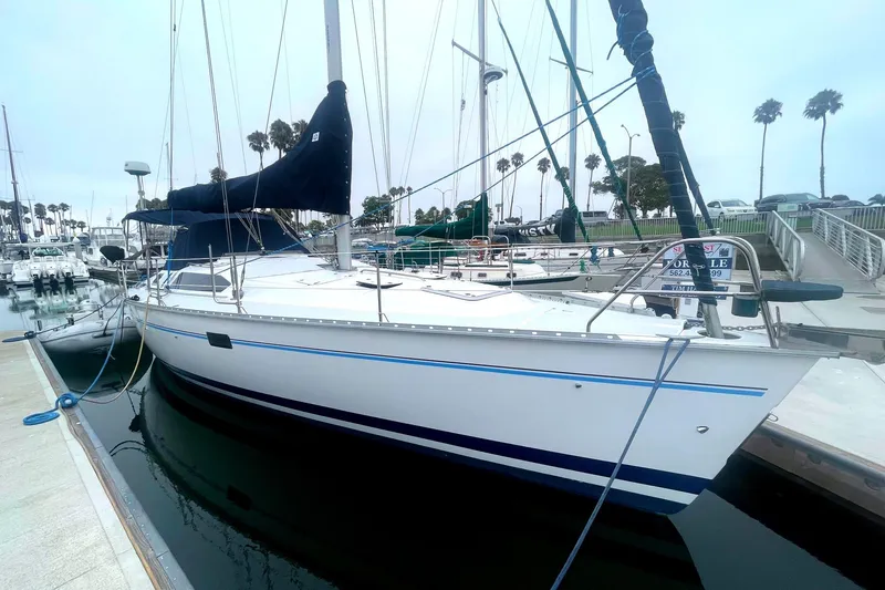 Sailboat Hunter 40.5, 1993 model, docked at marina with palm trees in background.