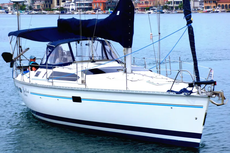 1993 Hunter 40.5 sailboat with blue canopy on calm water, coastal background.