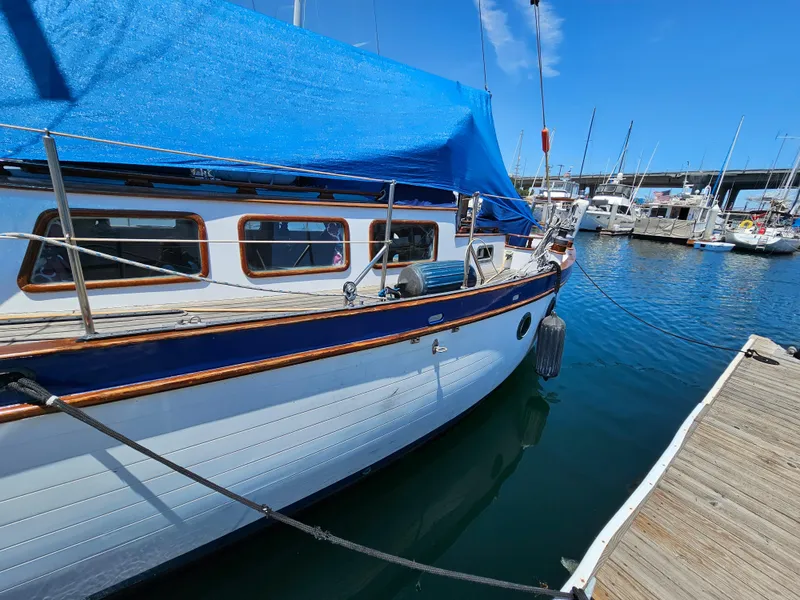1985 Spindrift Pilot House Cutter docked at a marina with blue tarp cover.