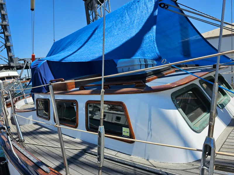 1985 Spindrift Pilot House Cutter with blue tarp cover docked at marina.