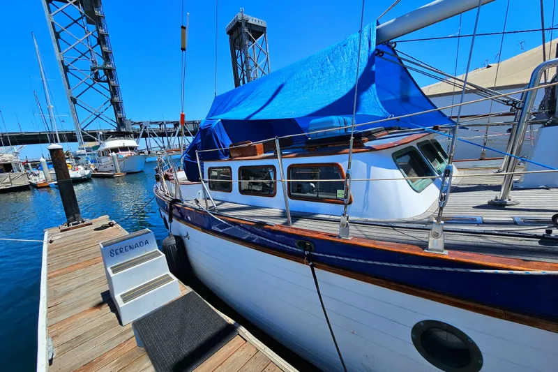 1985 Spindrift Pilot House Cutter docked at marina with blue tarp cover.