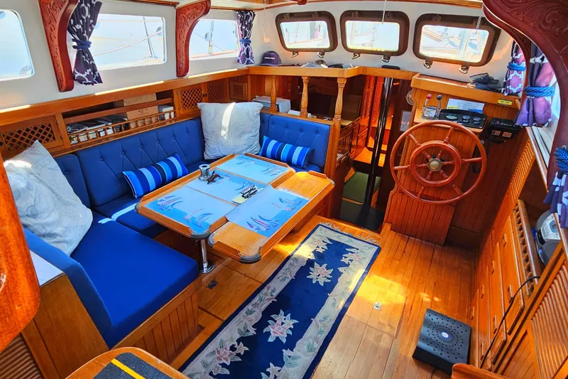 Interior of 1985 Spindrift Pilot House Cutter with wooden finishes and blue seating.