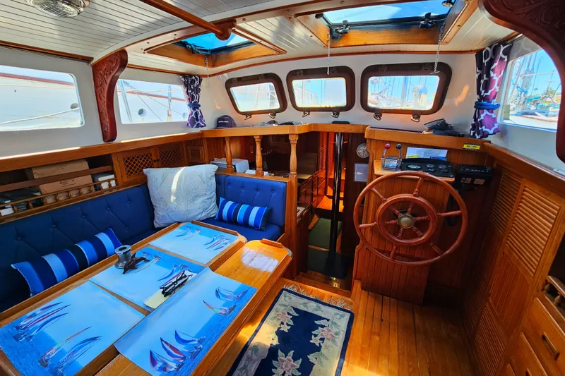 Interior of 1985 Spindrift Pilot House Cutter with wooden finishes and blue seating.
