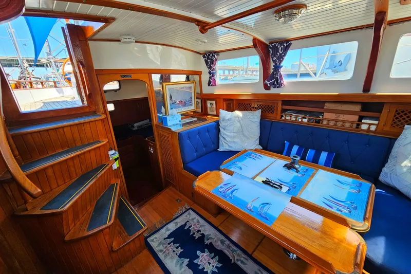 Interior of 1985 Spindrift Pilot House Cutter with wooden finishes and blue seating.