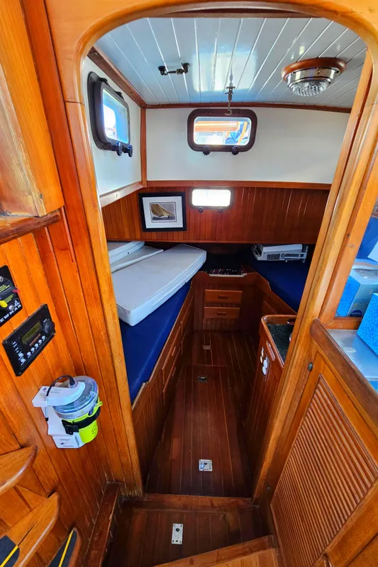 Interior of 1985 Spindrift Pilot House Cutter with wooden finishes and cozy sleeping area.