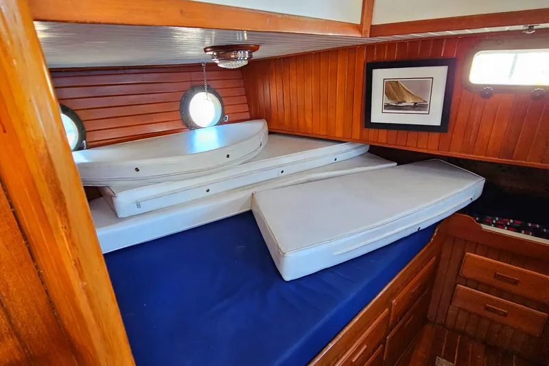 Interior cabin of 1985 Spindrift Pilot House Cutter with wooden paneling and stacked cushions.