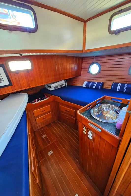 1985 Spindrift Pilot House Cutter cabin interior with wood paneling and blue cushions.