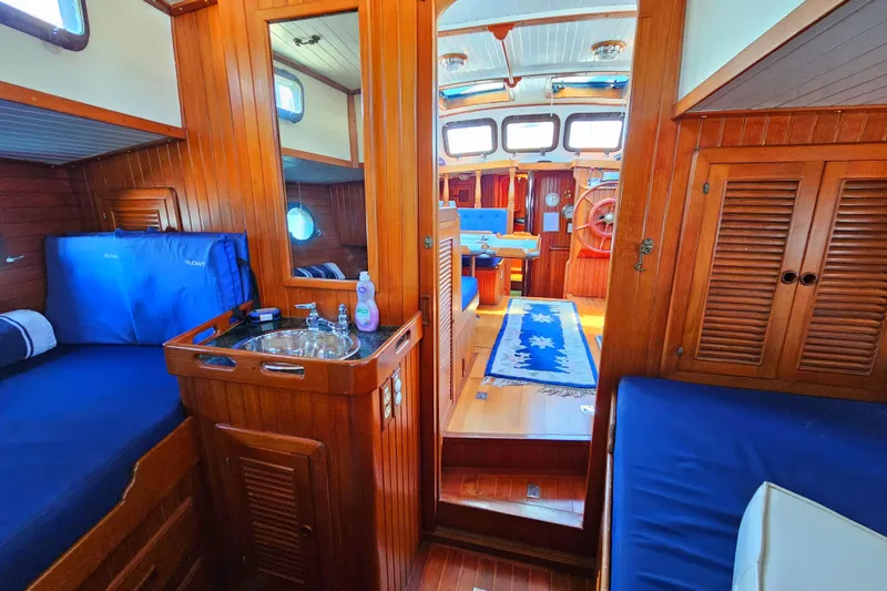 Interior of 1985 Spindrift Pilot House Cutter with wooden finishes and blue upholstery.