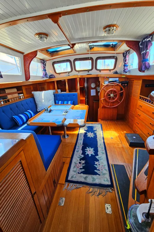 Interior of 1985 Spindrift Pilot House Cutter with wooden finishes and blue upholstery.