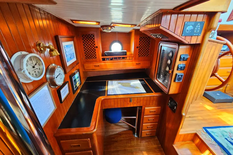 1985 Spindrift Pilot House Cutter navigation station with wooden interior, charts, and instruments.