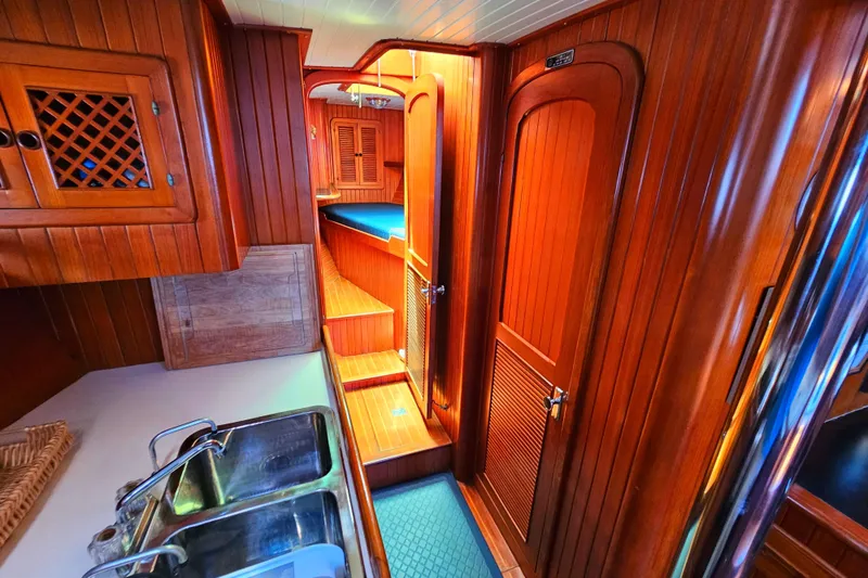 Interior of 1985 Spindrift Pilot House Cutter with wooden cabinetry and double sink.