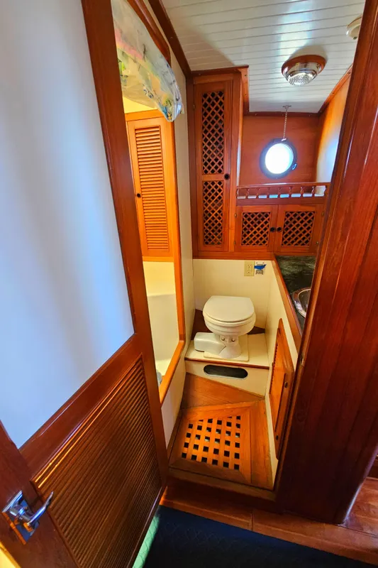 1985 Spindrift Pilot House Cutter bathroom with wooden cabinetry and porthole window.