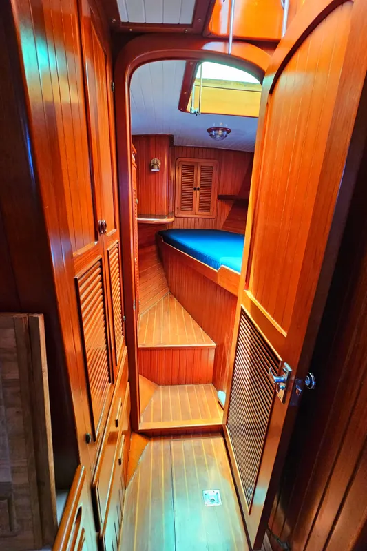 1985 Spindrift Pilot House Cutter interior with wooden finish and cozy sleeping area.
