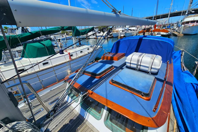 1985 Spindrift Pilot House Cutter docked at marina, blue cover, wooden deck.
