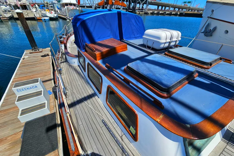 1985 Spindrift Pilot House Cutter docked at marina, featuring blue covers and wooden accents.