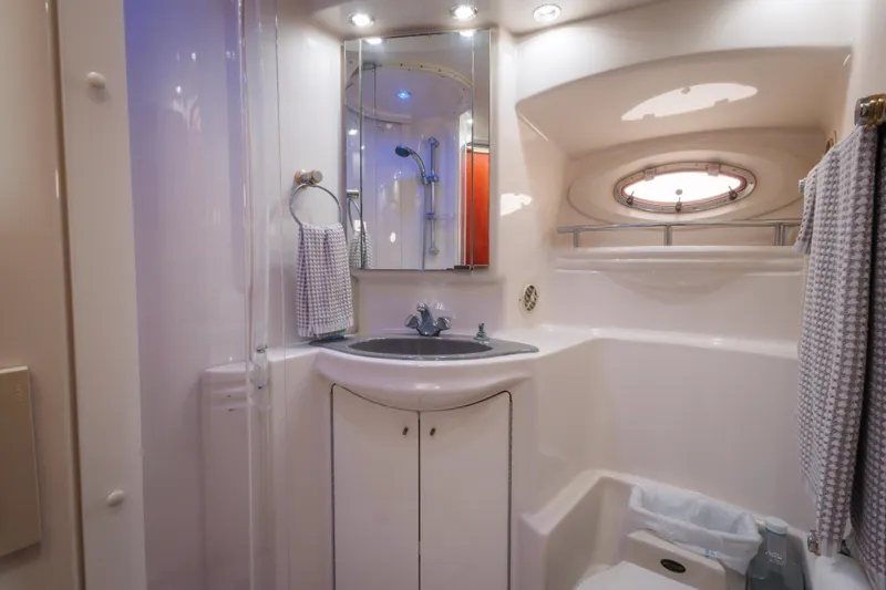 Luxurious bathroom in 1997 Maxum 4600 SCB yacht with modern fixtures and porthole window.