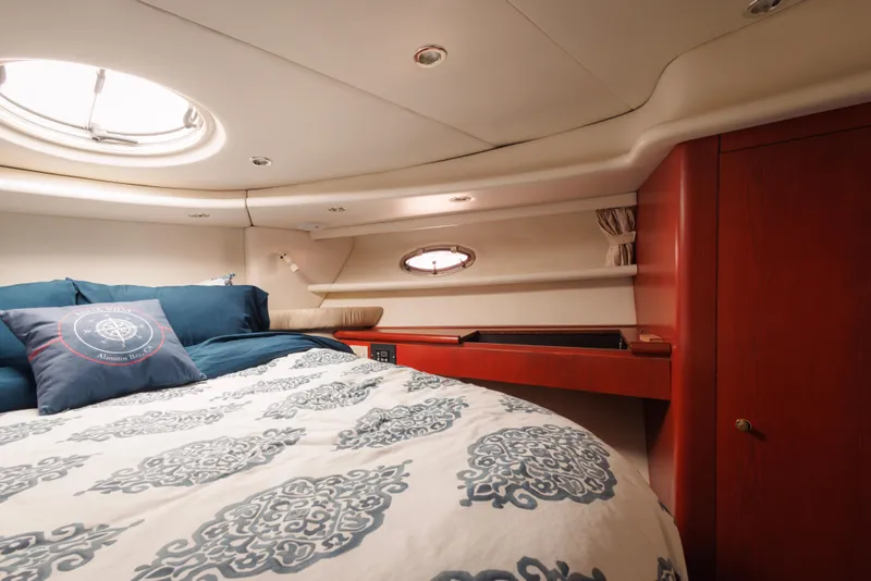 Luxurious cabin interior of 1997 Maxum 4600 SCB yacht with elegant bedding and wood accents.