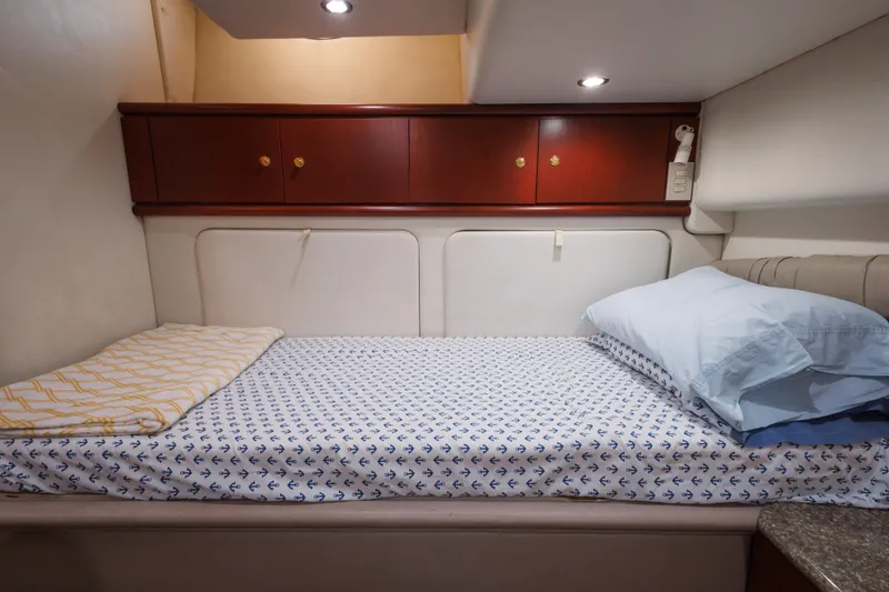 Cozy cabin bed in 1997 Maxum 4600 SCB yacht with anchor-patterned sheets.