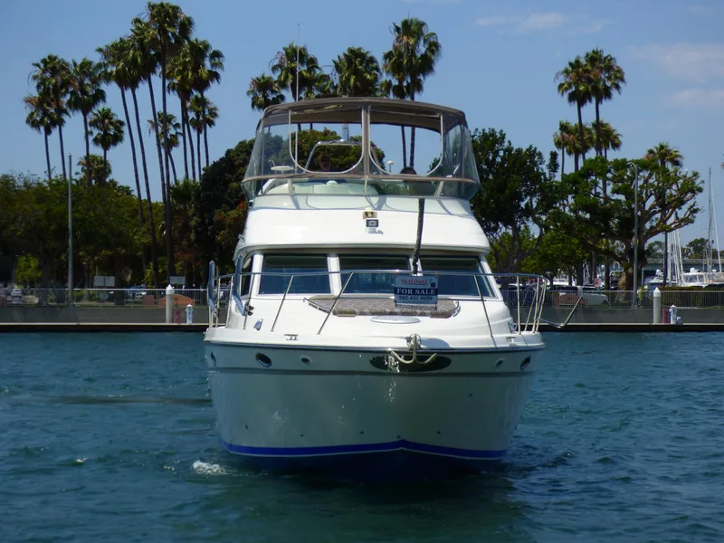 1997 Maxum 4600 SCB yacht on water, surrounded by palm trees, for sale.