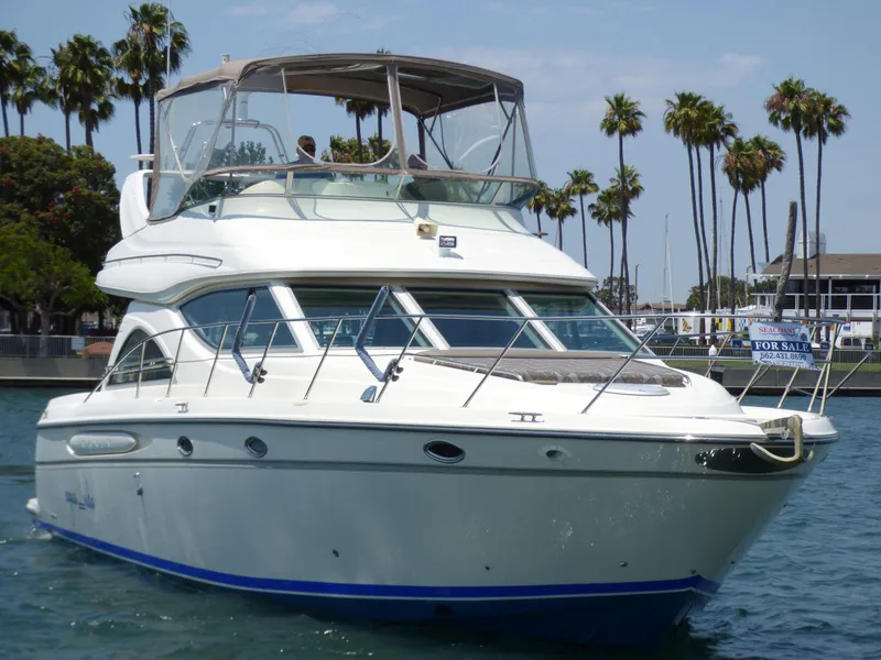 1997 Maxum 4600 SCB yacht on water, palm trees in background, for sale sign visible.