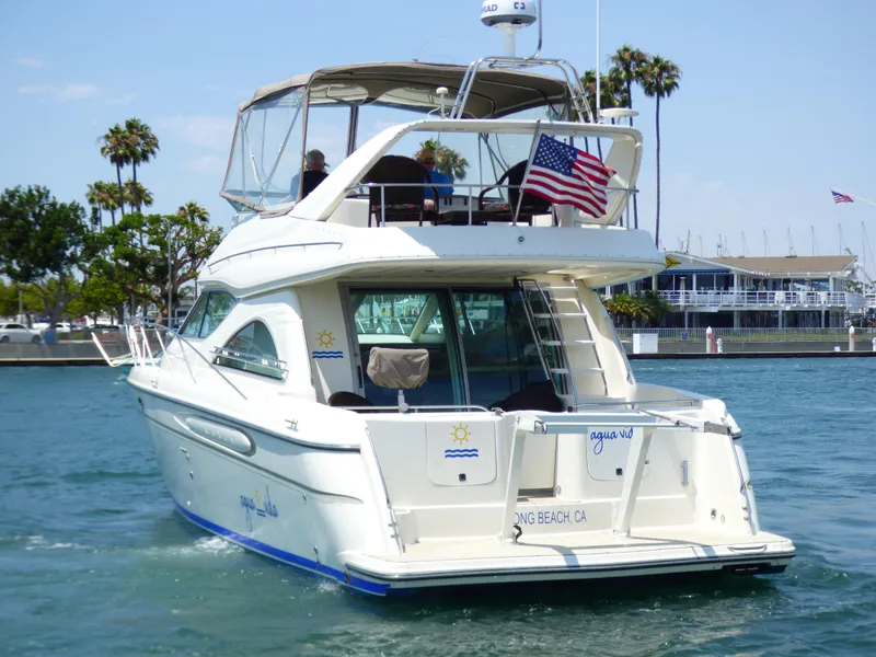 1997 Maxum 4600 SCB yacht cruising in a marina with American flag.