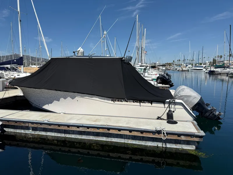 2005 Grady-White Bimini 306 boat docked with cover, surrounded by marina and sailboats.