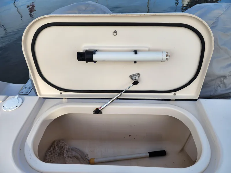 Open storage compartment on 2005 Grady-White Bimini 306 boat, featuring a net and handle.