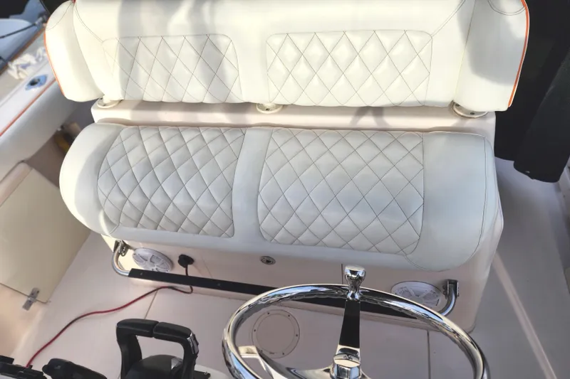 2005 Grady-White Bimini 306 boat interior with quilted white seating and steering wheel.