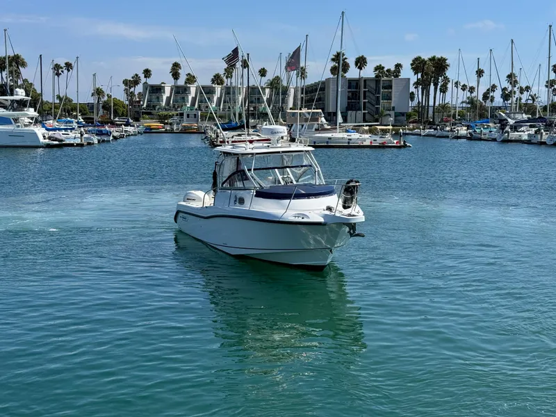 2008 Boston Whaler 285 Conquest boat in a marina with palm trees and buildings.