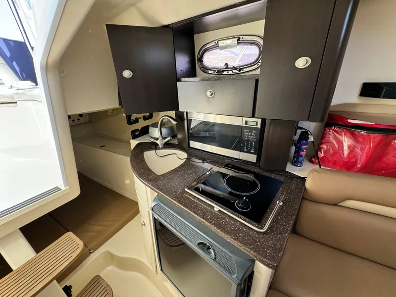 2008 Boston Whaler 285 Conquest cabin kitchen with microwave, stove, and storage cabinets.