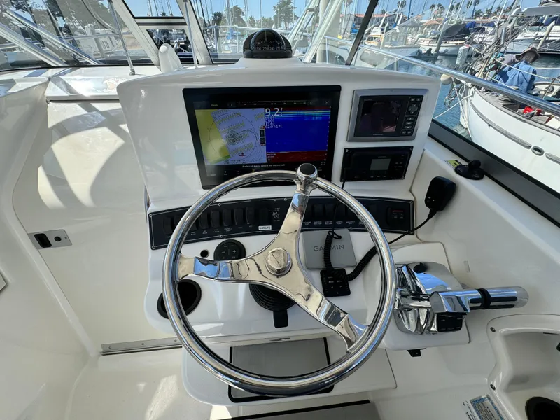 Helm of 2008 Boston Whaler 285 Conquest with navigation screens and steering wheel.