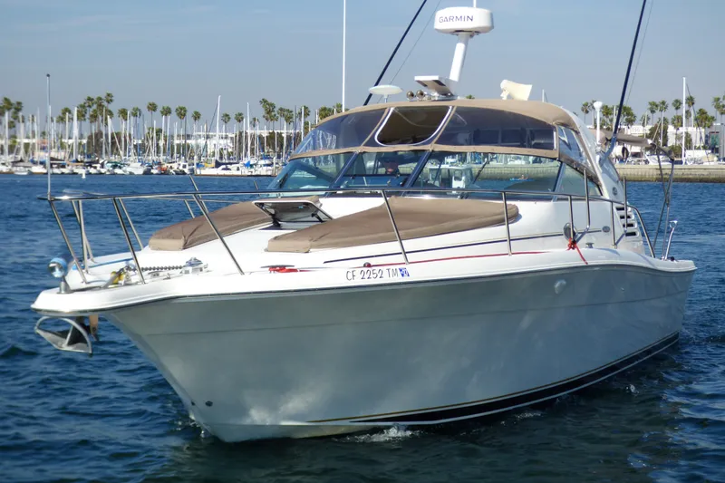 2002 Sea Ray 340 Amberjack boat on water, marina background, clear sky.
