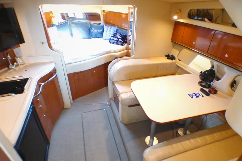 Interior of 2002 Sea Ray 340 Amberjack, featuring cozy seating and a compact kitchen area.