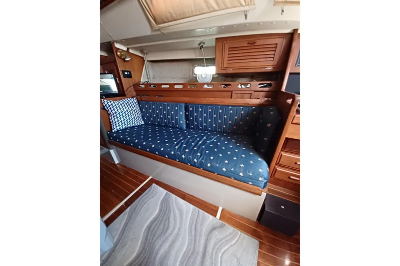 1987 O'Day 40 yacht interior with blue star-patterned seating and wooden cabinetry.