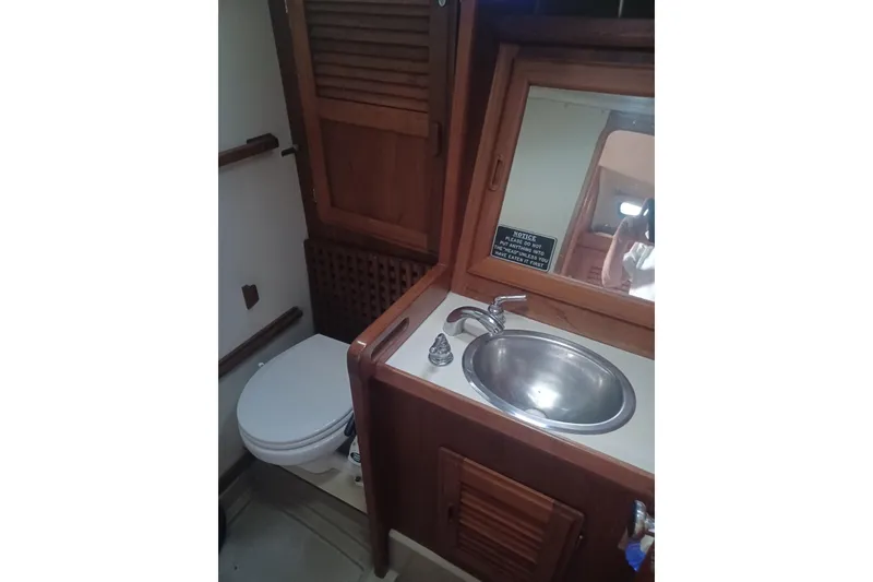 1987 O'Day 40 yacht bathroom with wooden cabinetry, sink, and toilet.