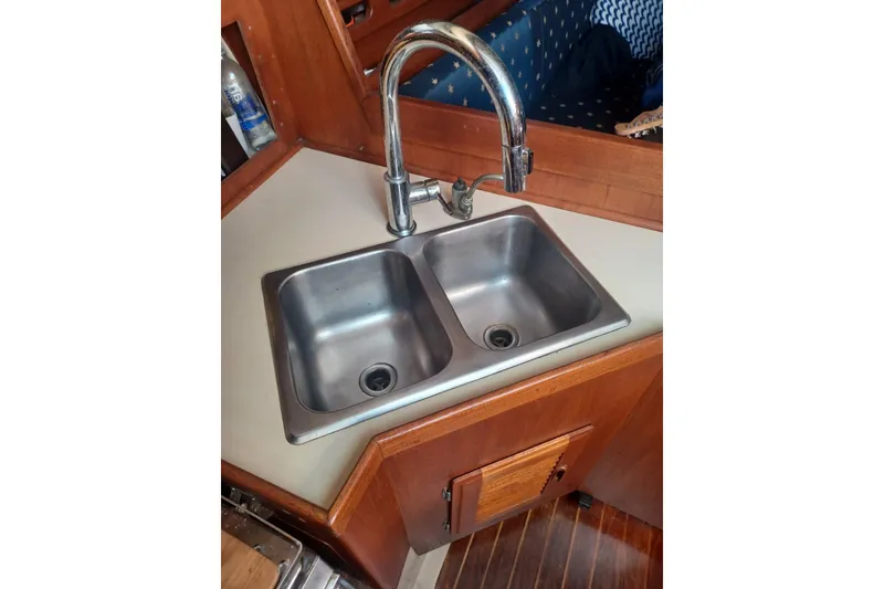 Double sink in 1987 O'Day 40 yacht galley with wooden cabinetry.