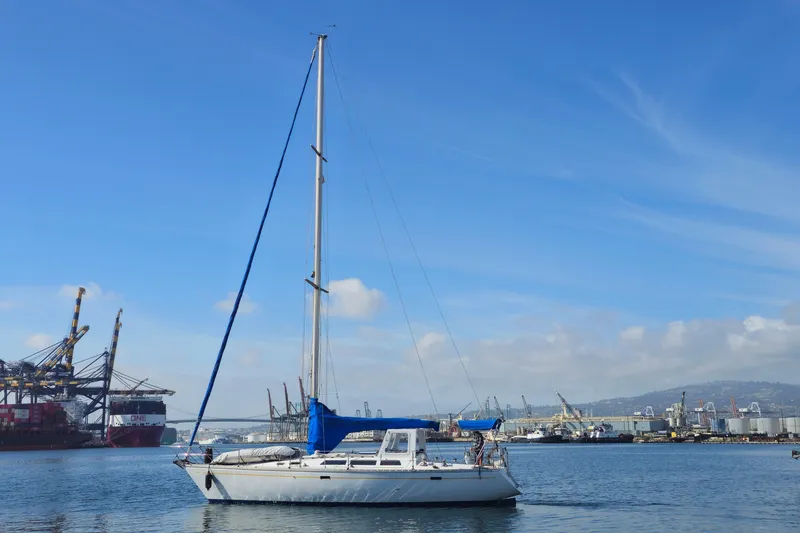 1987 O'Day 40 sailboat in a bustling harbor with cranes and ships.