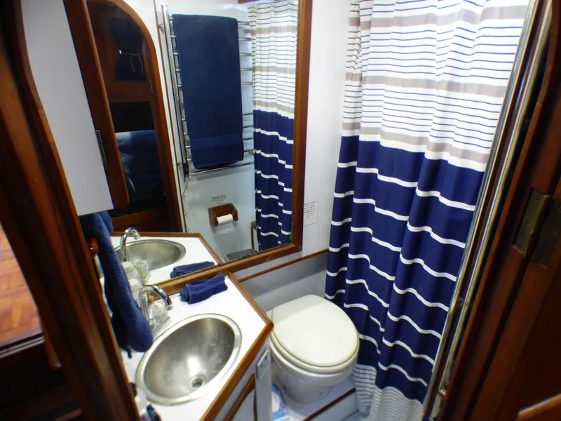 1980 CHB Heritage 42 Trawler bathroom with sink, toilet, and striped shower curtain.