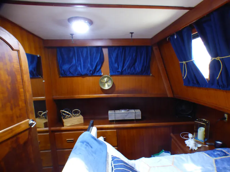1980 CHB Heritage 42 Trawler cabin with wooden interior and blue curtains.