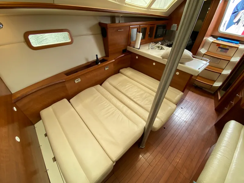 Interior of 2012 Hunter e36 sailboat with convertible seating and wooden flooring.