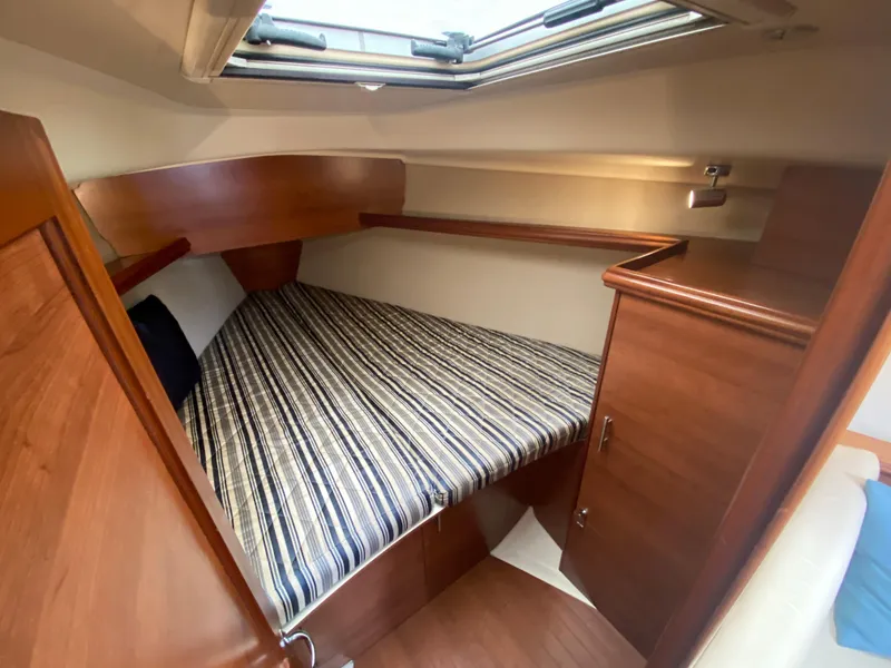 Cozy cabin interior of 2012 Hunter e36 sailboat with striped bedding and wooden furnishings.