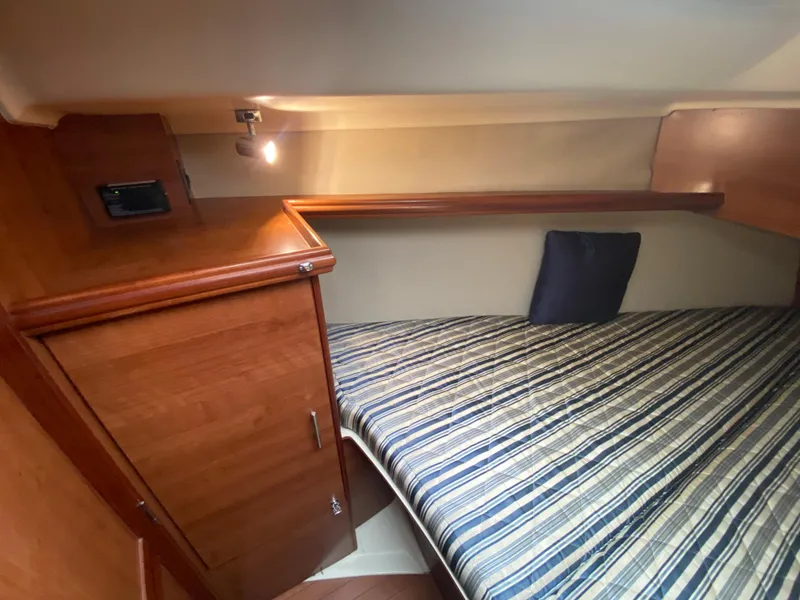 Hunter e36 2012 boat cabin with striped bedding and wooden storage.